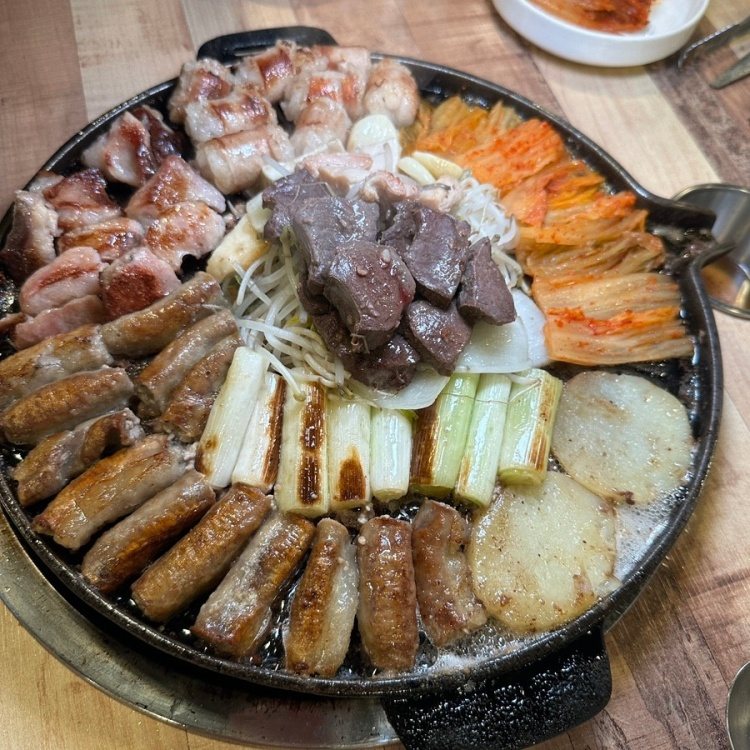 둥근 판 둘레에 구운 곱창을 두르고 가운데 염통, 숙주, 대파, 감자, 김치를 올린 모듬구이